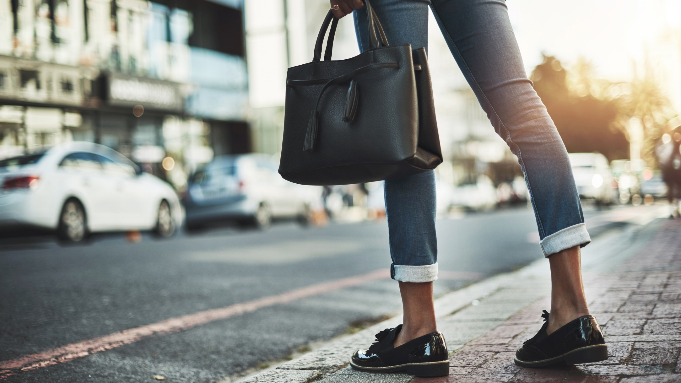 Women holding a black bag crossing a street