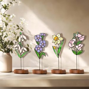 Handmade stained glass birth flowers featuring Snowdrop, Violet, Daffodil, and Sweet Pea, elegantly displayed on wooden bases with a soft floral background. A perfect personalized Mother’s Day gift, unique floral decor, and thoughtful birthday present for garden lovers.